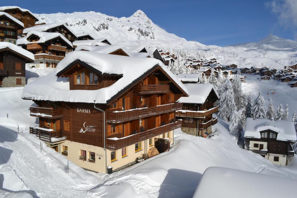 a ski lodge in the snow with mountains in the background at Hotel Slalom in Bettmeralp