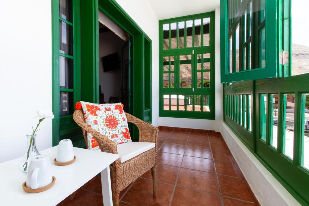 ヤイサにあるB&B Hotelito el Campoの緑の壁のポーチ(白いテーブルと椅子付)