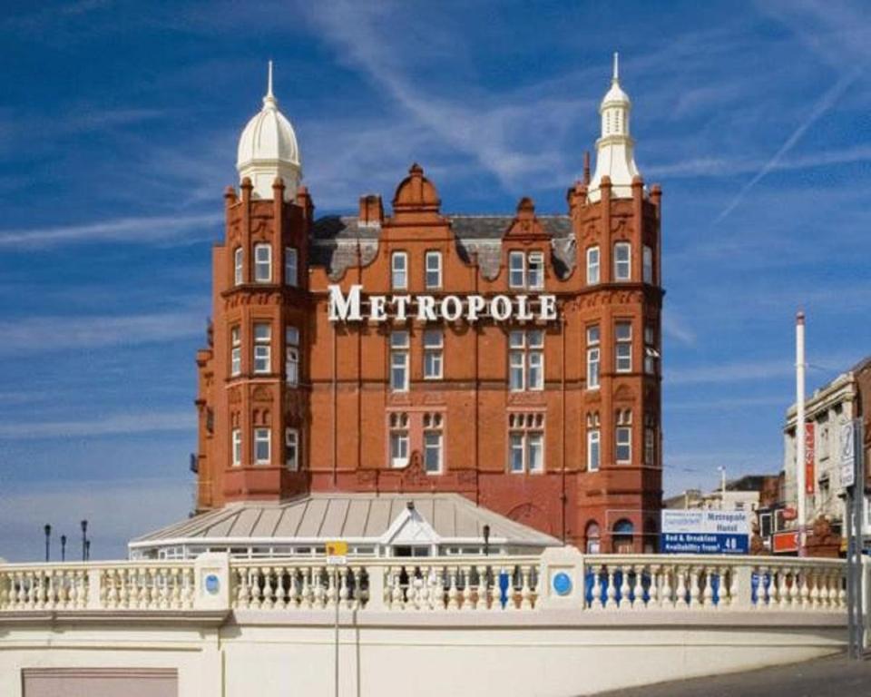 um grande edifício de tijolos vermelhos com um sinal nele em The Metropole Hotel em Blackpool