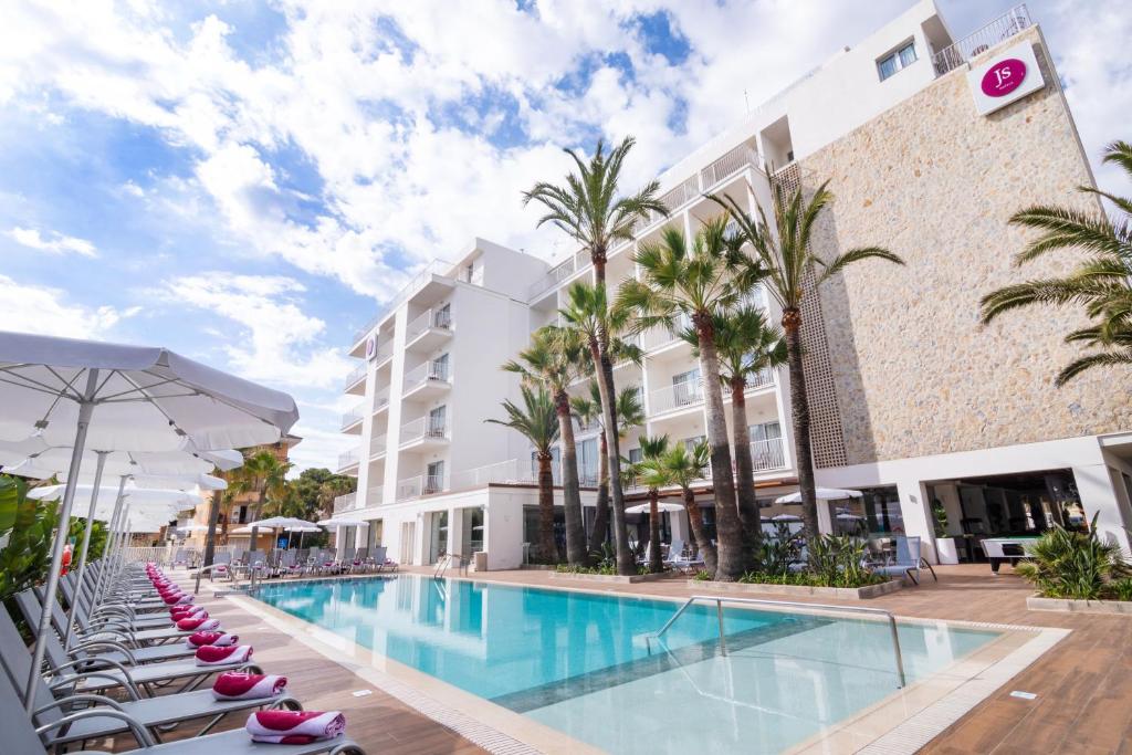 a pool at a hotel with lounge chairs and a building at JS Yate in Can Picafort