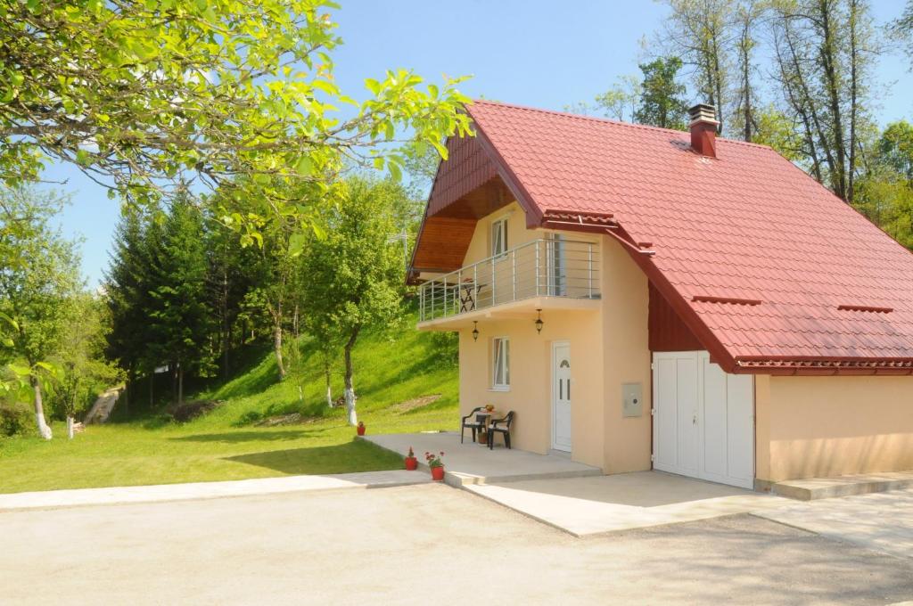 uma casa com um telhado vermelho e uma garagem em Village House Aleksic em Pošćenje