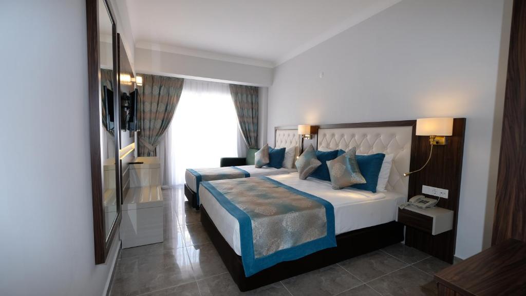 a bedroom with a large bed with blue pillows at Cleopatra Golden Beach Hotel in Alanya