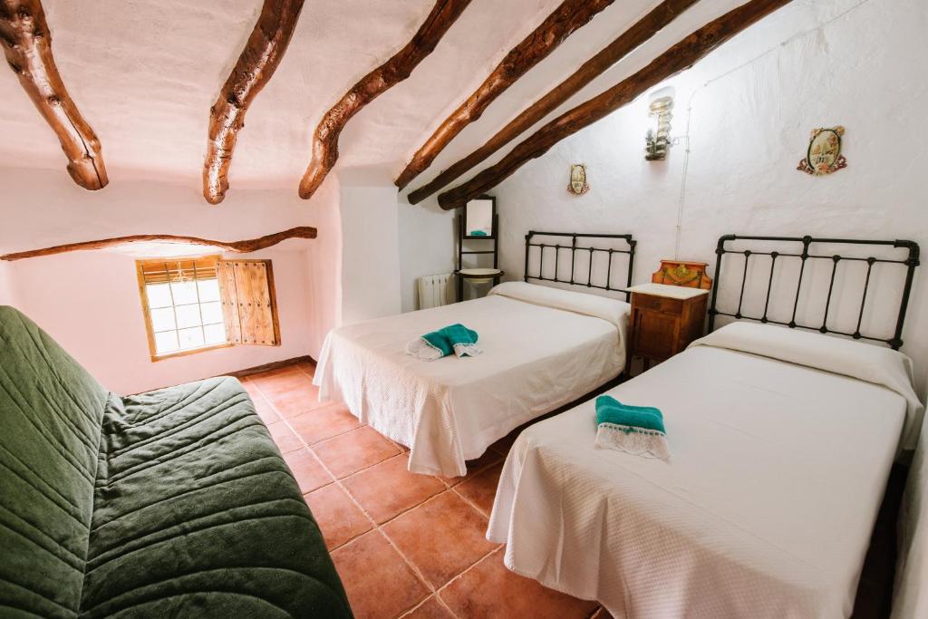 sypialnia z 2 łóżkami i kanapą w obiekcie Cortijo Rural Majolero w mieście Castillo de Locubín