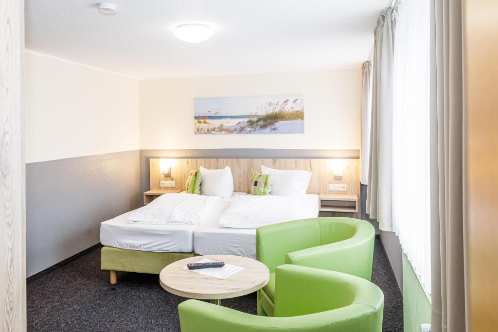 um quarto de hotel com uma cama, uma mesa e cadeiras em Gästehaus Alexandra em Cuxhaven