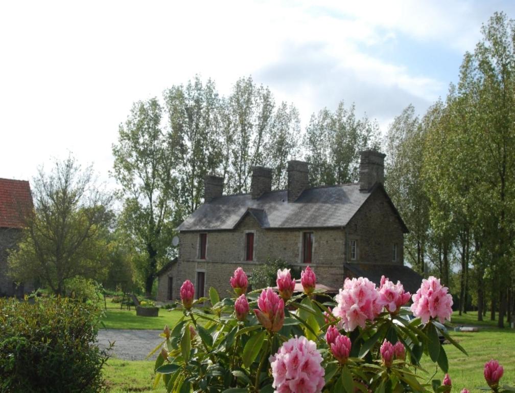 una casa vieja con flores rosas delante en Le Manoir du Butel, en Saint-Amand