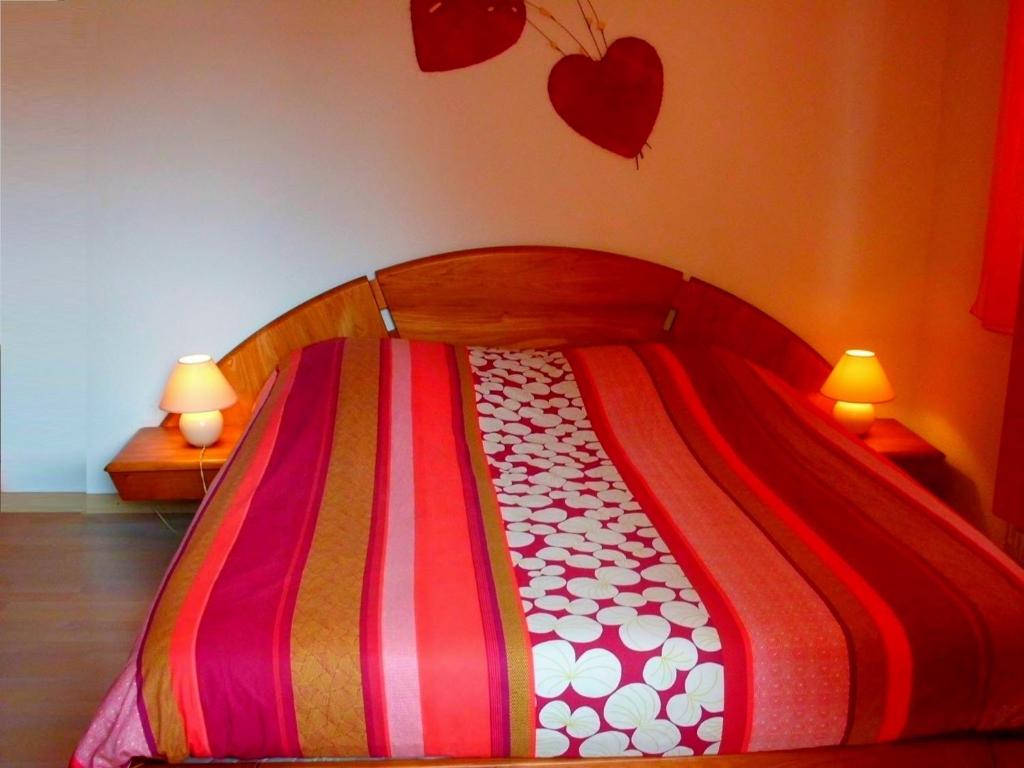 a bed with a colorful blanket and two lamps at Gite Dans Cité Médievale in Boersch
