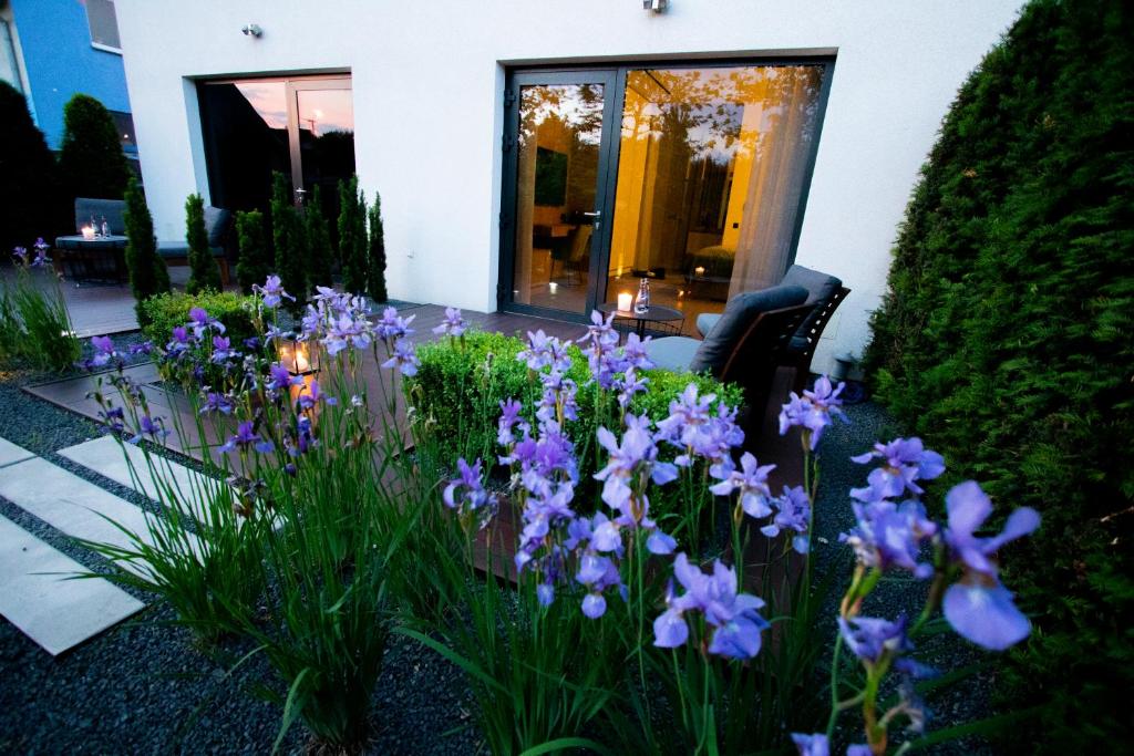 un jardin avec des fleurs violettes en face d'une maison dans l'établissement Apartamenty 242, à Toruń