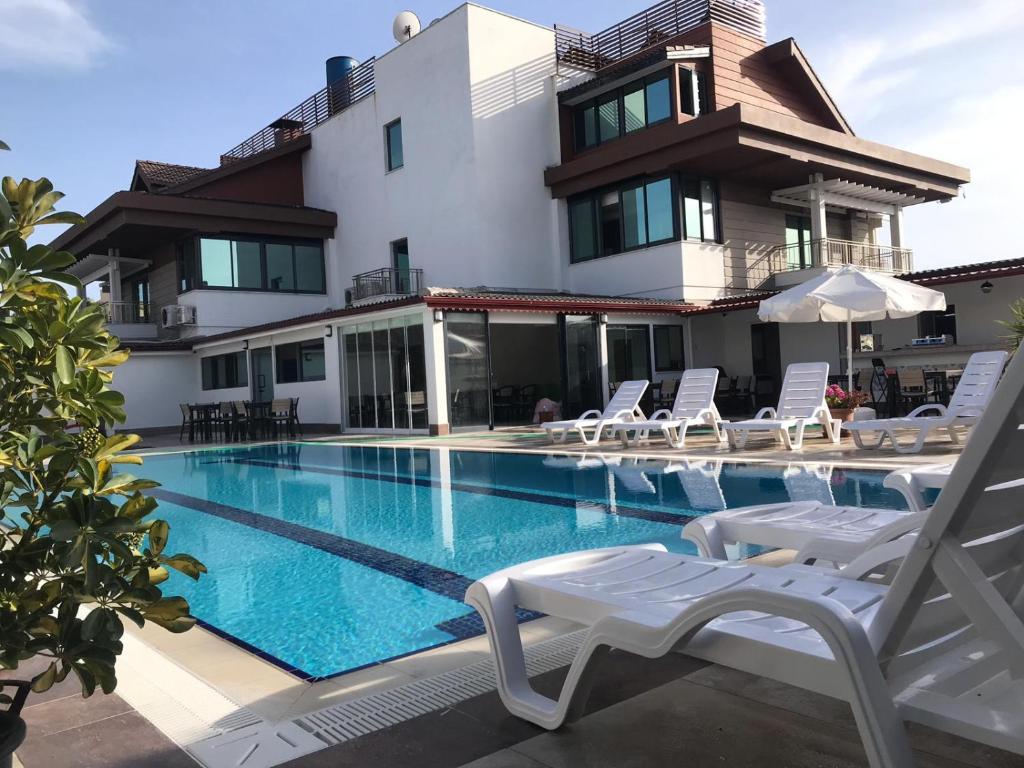 a swimming pool with chairs and a house at Oyster Boutique Hotel in Side