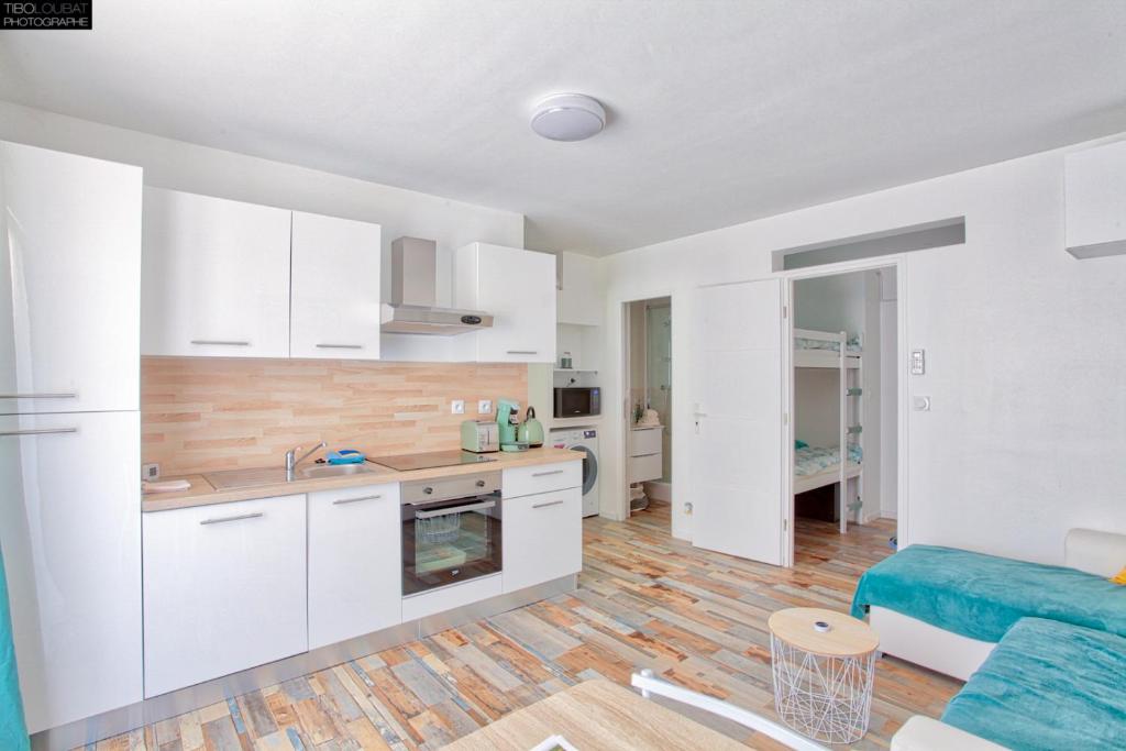 uma cozinha e sala de estar com armários brancos e um sofá azul em T2 PRESTIGE BANDOL em Bandol