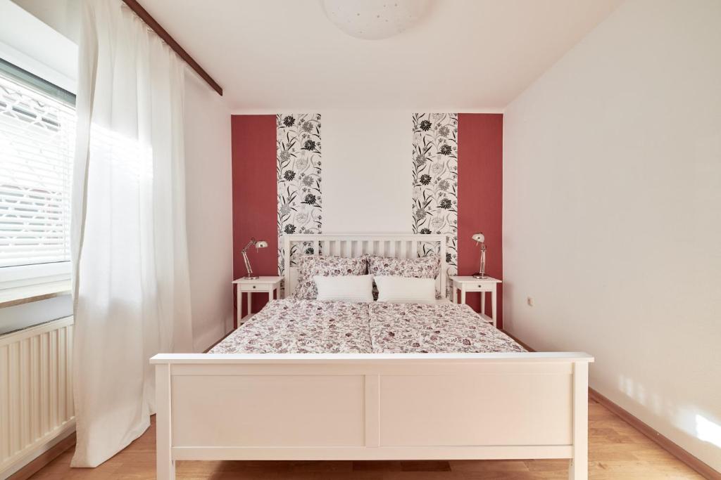 een wit bed in een witte slaapkamer met rode muren bij Ferienwohnung AOLI in Gmunden