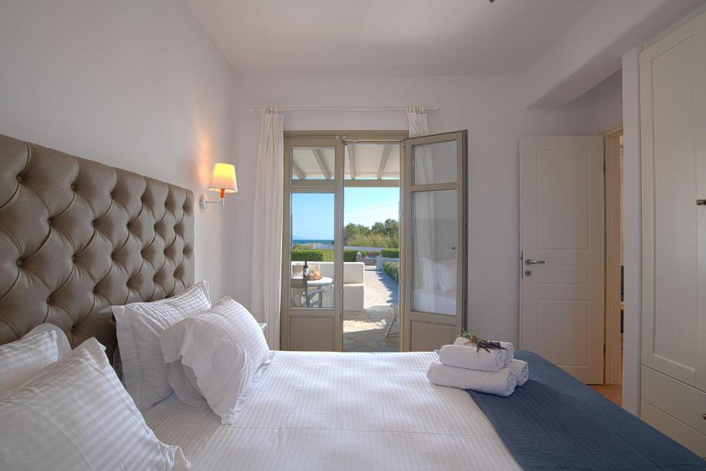 a bedroom with a large white bed with a large headboard at Golden Sand Paros in Chrissi Akti