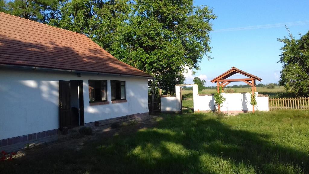 una casa blanca con cenador en un patio en Darutollas Vendégház en Ópusztaszer