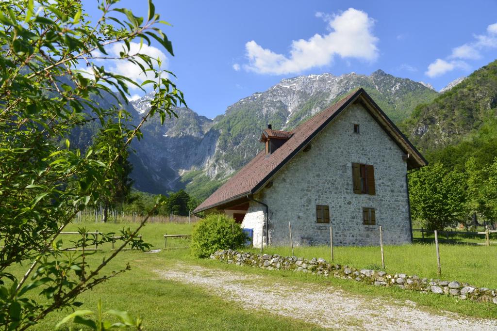 een oud huis in een veld met bergen op de achtergrond bij Agriturismo Pian dei Tass in Barcis