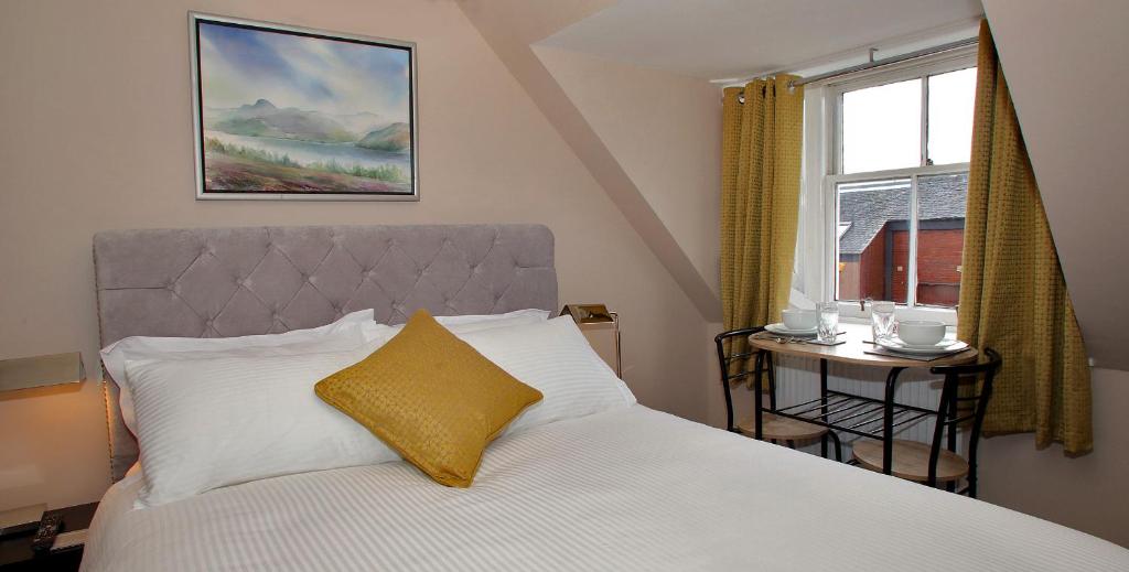 1 dormitorio con cama con almohada amarilla y ventana en Paton Cottage en Inverness