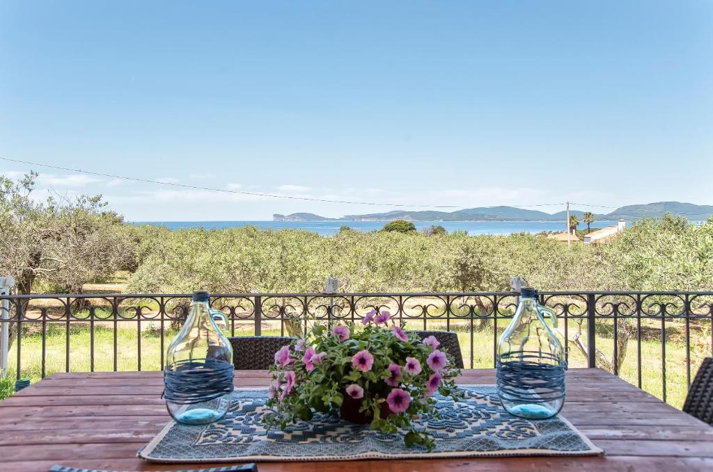 Brassol Casa Vacanze Vista Mare في ألغيرو: طاولة خشبية مع كأسين من النبيذ وترتيب الزهور