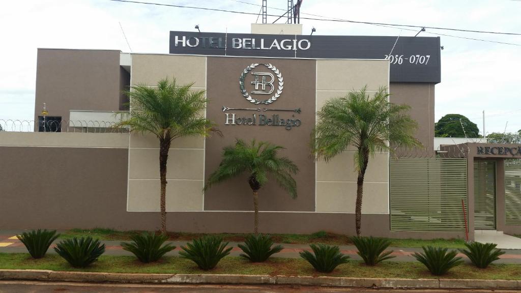 a hotel with palm trees in front of a building at Hotel Bellagio in Campo Grande