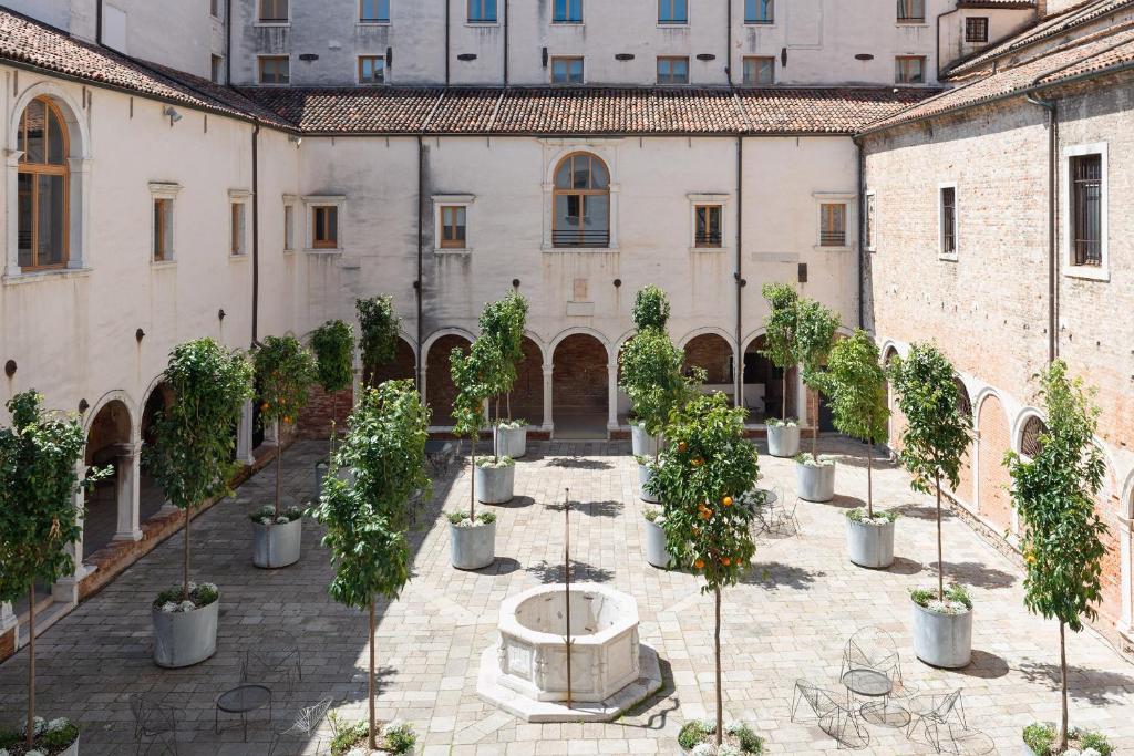 einen Innenhof mit Topfbäumen und einem Brunnen in der Unterkunft Combo Venezia in Venedig