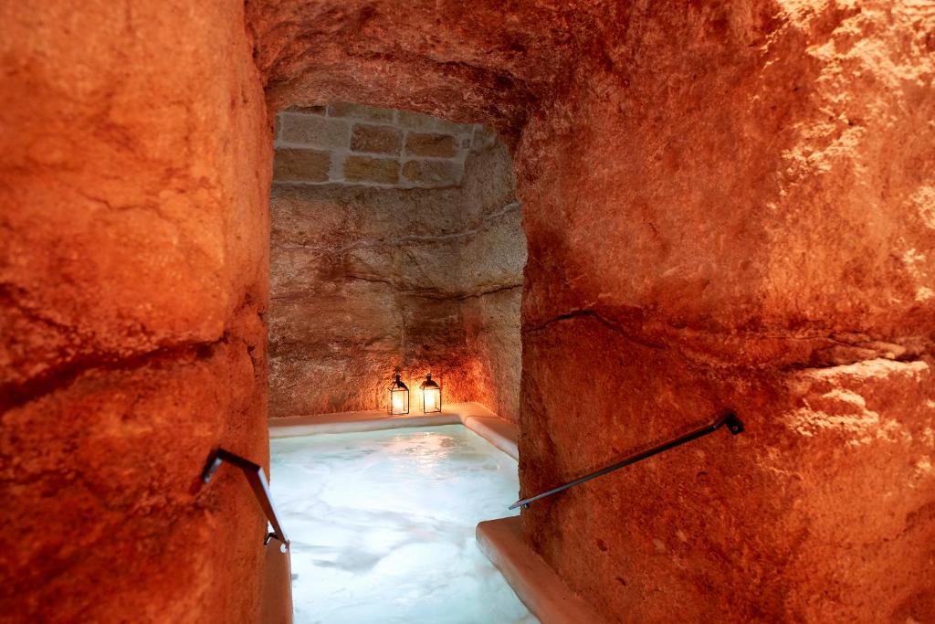 a swimming pool in a cave with a stone wall at Musae Relais & SPA in Polignano a Mare