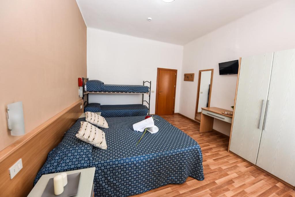 a small room with a bed with blue sheets and pillows at Hotel Miramare in Marotta