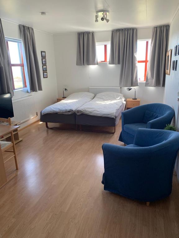 Drangsnes的住宿－Sunna's Guesthouse，一间卧室配有一张床和两张蓝色椅子