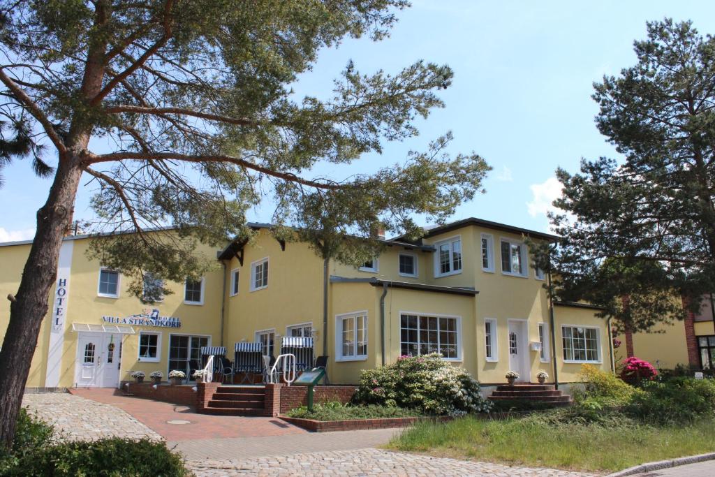 ein gelbes Gebäude mit einem Baum davor in der Unterkunft Hotel Villa Strandkorb in Graal-Müritz