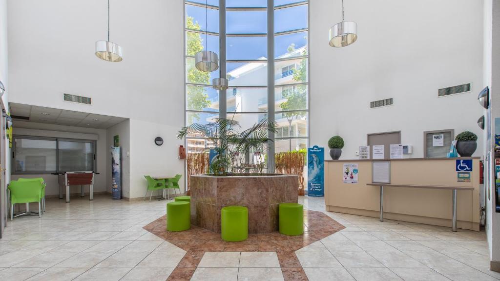 a large room with a potted plant in the middle at Vacancéole - Résidence Le Crystal in Cagnes-sur-Mer