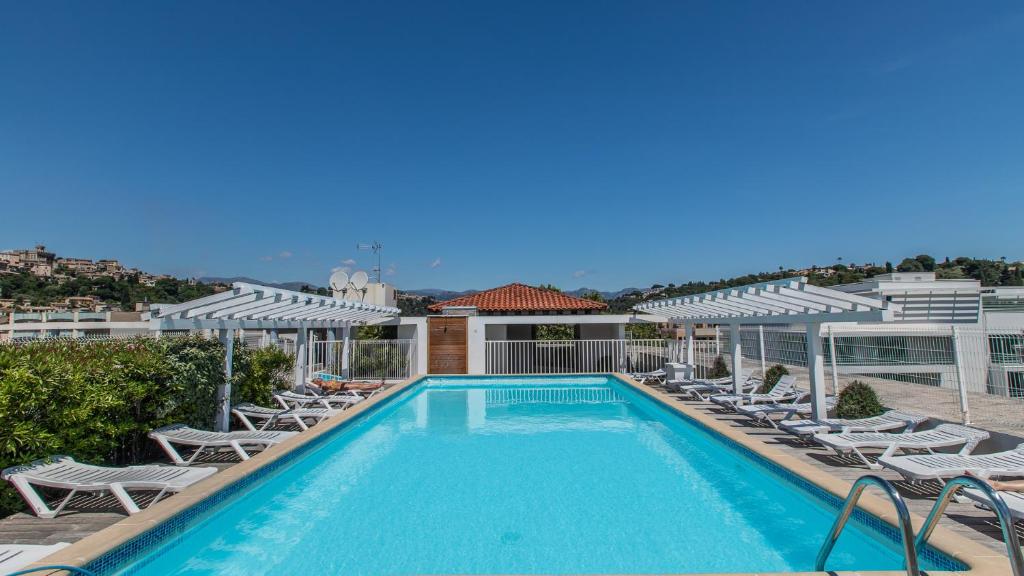 - une piscine avec chaises longues et un complexe dans l'établissement Vacancéole - Résidence Le Crystal, à Cagnes-sur-Mer