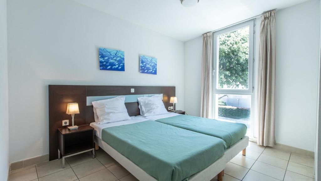 a bedroom with a bed and a large window at Vacancéole - Résidence Le Crystal in Cagnes-sur-Mer