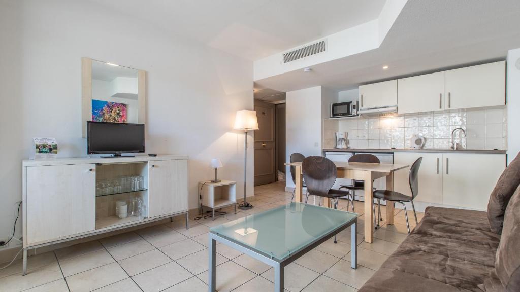 a living room with a couch and a table at Vacancéole - Résidence Le Crystal in Cagnes-sur-Mer