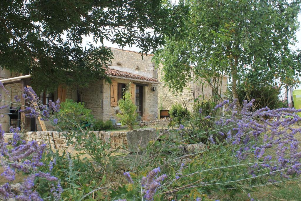 einen Garten mit lila Blumen vor einem Steinhaus in der Unterkunft GITE DES CHOUETTES in Muron