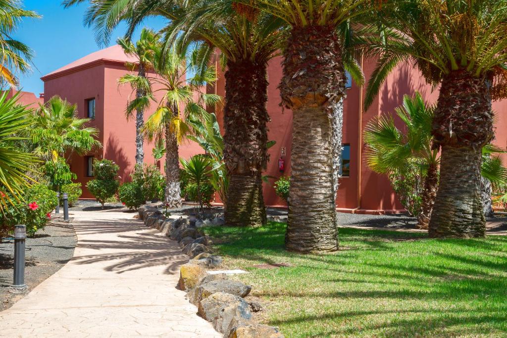 a row of palm trees in front of a red building at El Jasmine in Corralejo