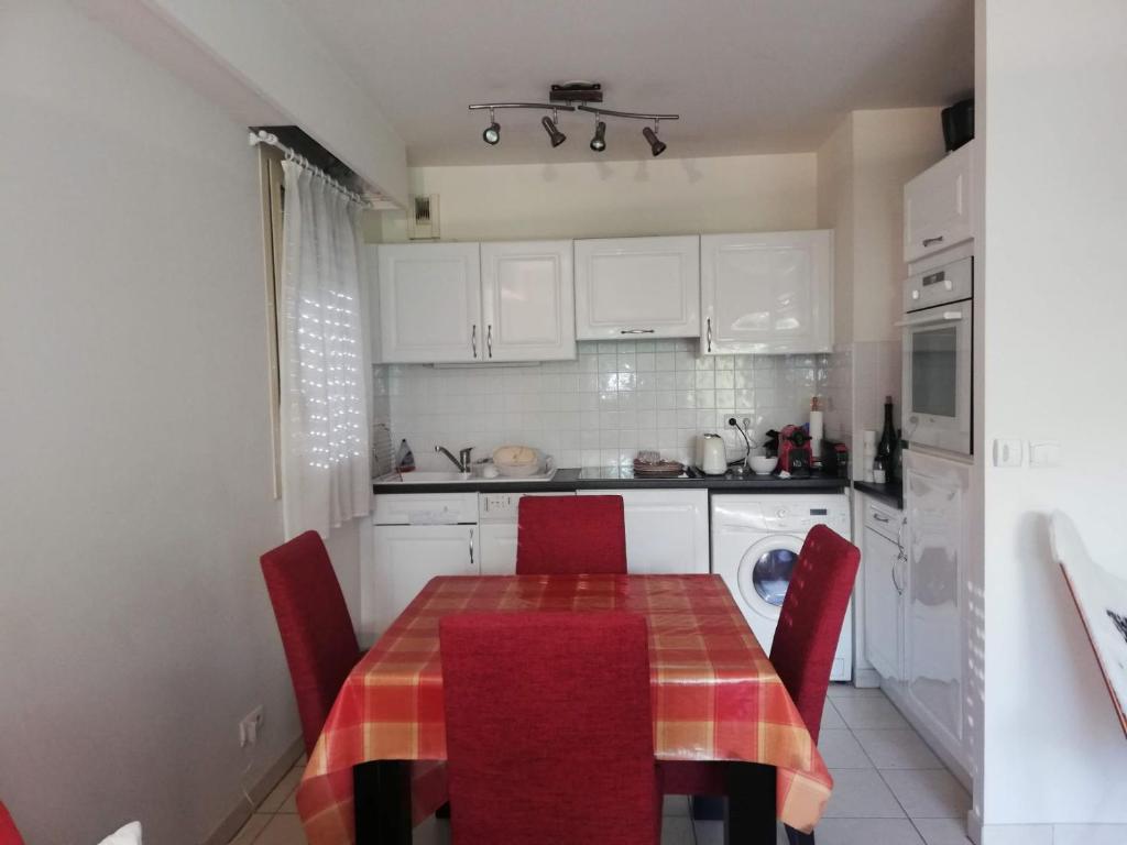 une cuisine avec une table et des chaises rouges et une cuisine avec des placards blancs dans l'établissement Villa Salammbo, à Antibes