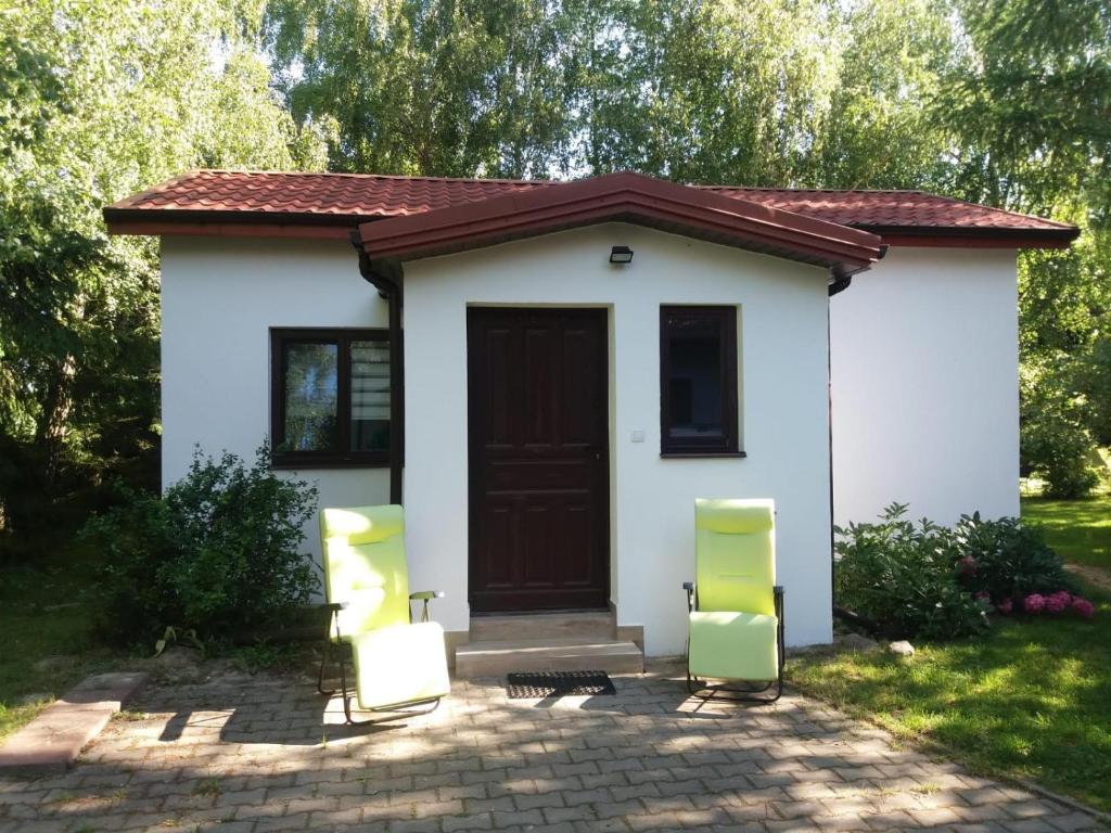 ein kleines weißes Haus mit zwei Stühlen davor in der Unterkunft Maly bialy domek pod brzozami in Nałęczów