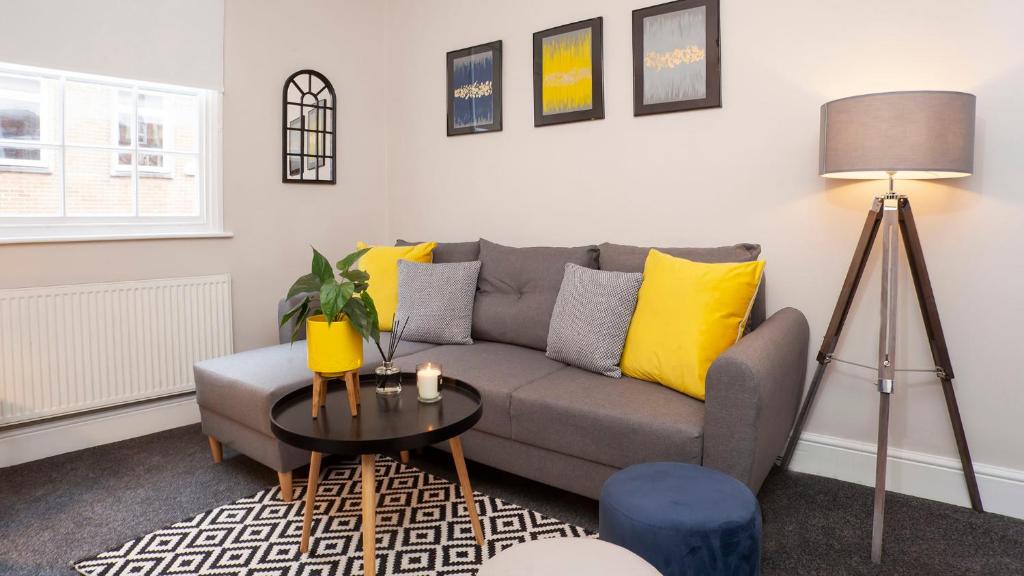 a living room with a gray couch and yellow pillows at Stylish and most central 2 bed City Centre Apartment in York