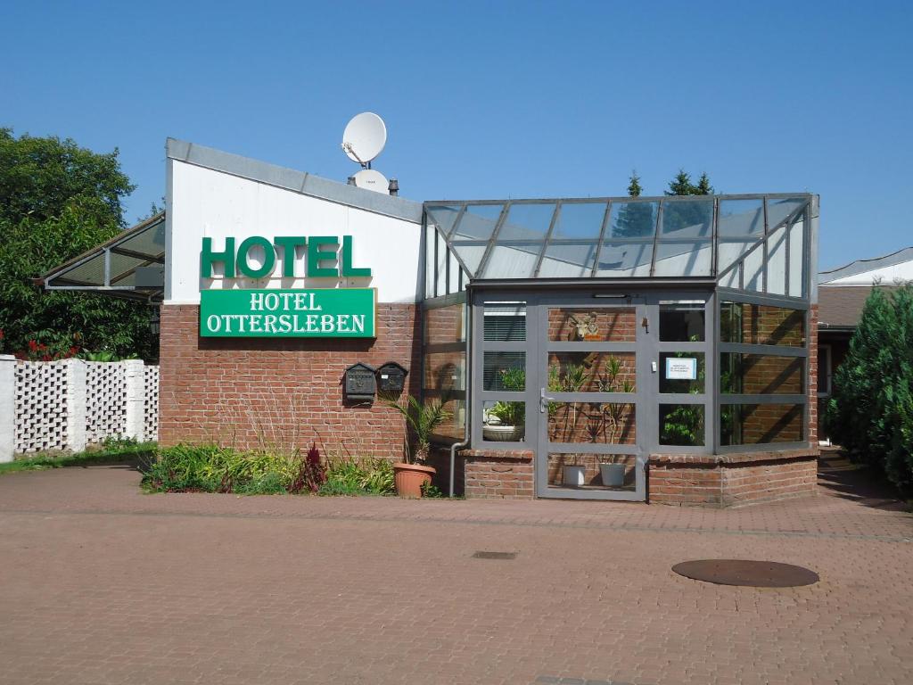 un hôtel avec un panneau sur le côté d'un bâtiment dans l'établissement Hotel Ottersleben, à Magdebourg