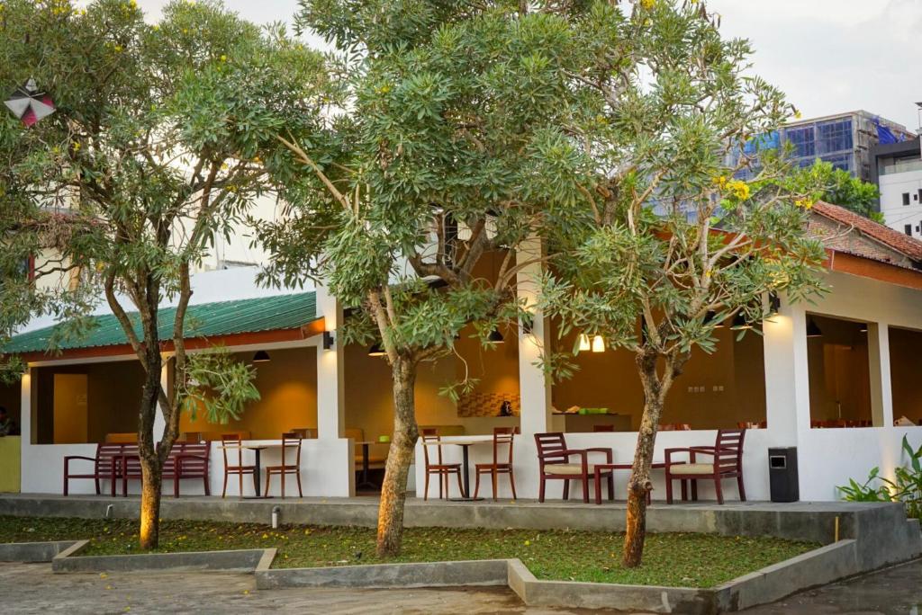 a restaurant with tables and chairs between two trees at The Capsule Malioboro in Yogyakarta