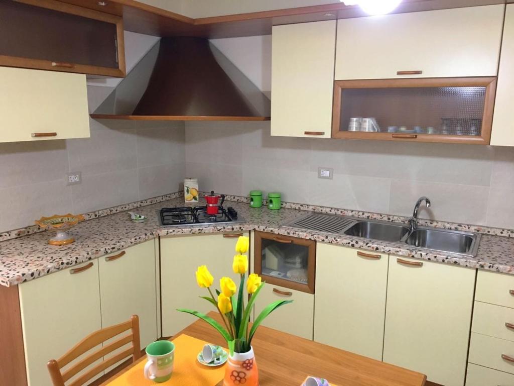 uma cozinha com armários brancos e uma mesa com flores amarelas em Appartamento Via Mentana em Scicli