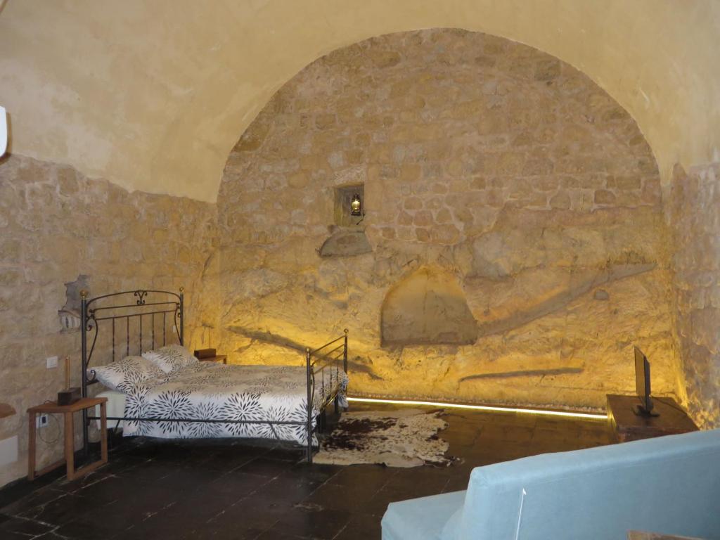 a room with a bed in a stone wall at la Postierla in Modica