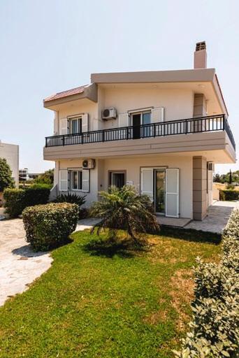 a house with a balcony on top of a yard at Gennadi Villa Del Mar in Gennadi