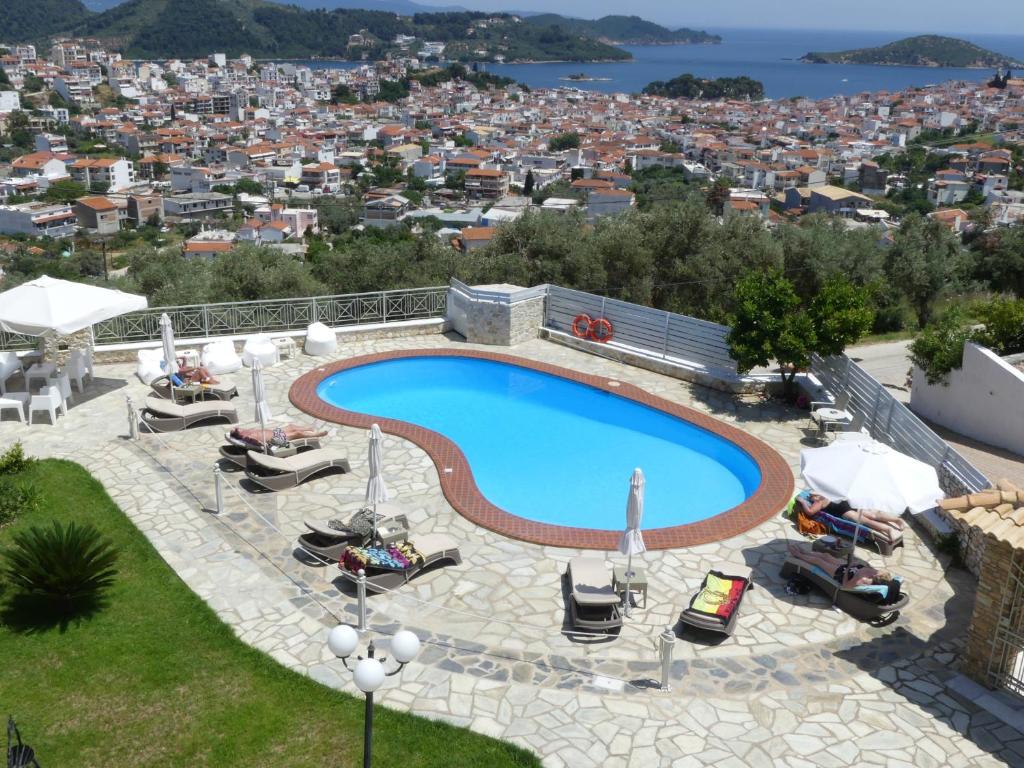 a swimming pool with chairs and a city in the background at Blue Horizon Studios in Skiathos
