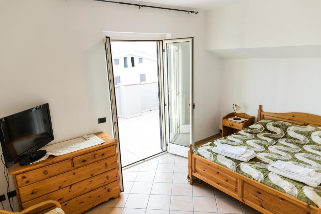 1 dormitorio con 1 cama, TV y balcón en Torre Ancinale, en Soverato Marina