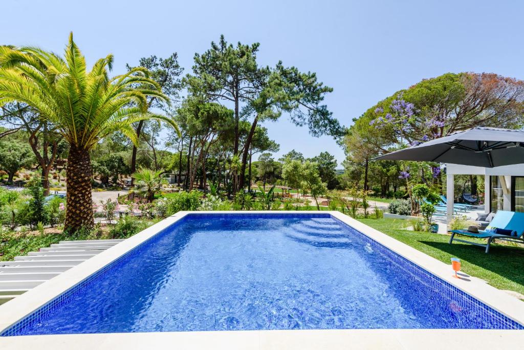 a swimming pool in a yard with an umbrella at Casa da Calma in Vale do Lobo