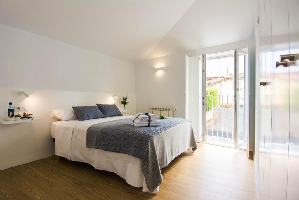 a white bedroom with a bed and a large window at Casa Adro in Melide