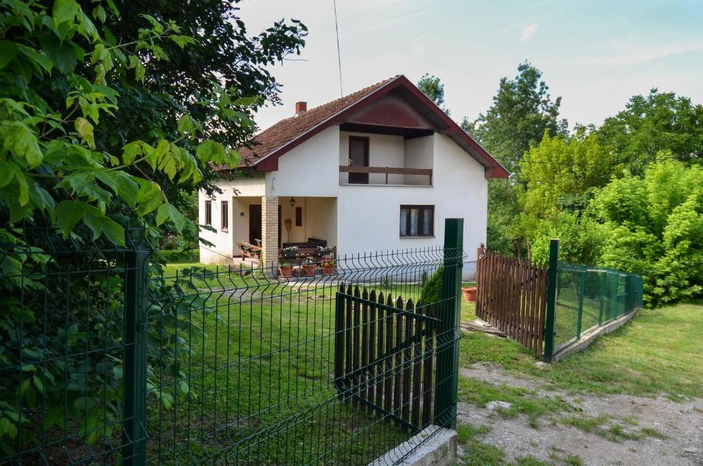 a fence in front of a white house at Kuca za odmor Radovanovic in Despotovac