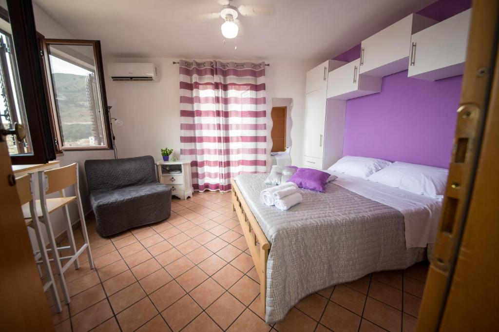 1 dormitorio con 1 cama de color púrpura y 1 silla en 'A Cumerdia - Casa Vacanze, en Castellammare del Golfo