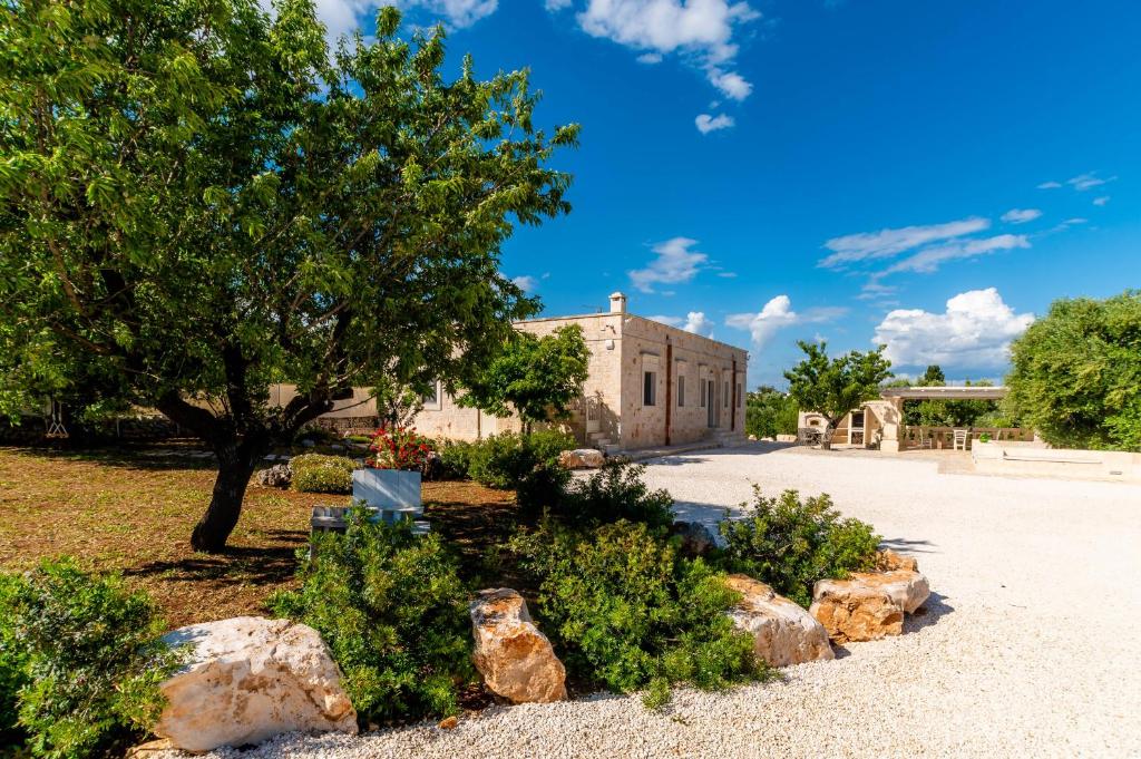 a building with a tree and rocks in a yard at Villa Vittoria in Cisternino