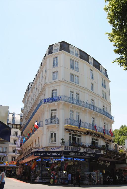 een hoog wit gebouw met een bord erop bij Hôtel Royal in Lourdes