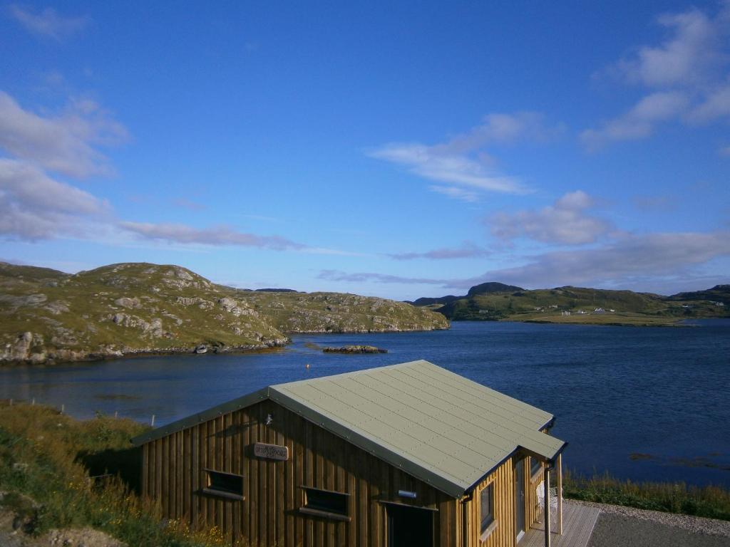 un piccolo edificio in legno accanto a un corpo d'acqua di Otter Bunkhouse a Cairisiadar