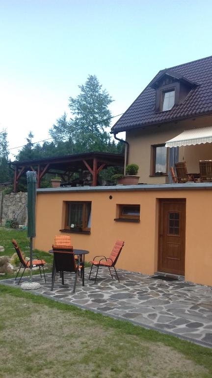 a patio with chairs and a table in front of a house at Apartmán Relax Hamry in Nové Hamry