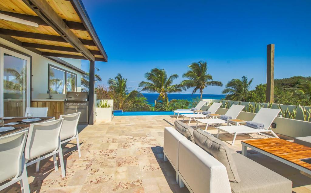 un patio esterno con tavoli, sedie e vista sull'oceano di Villa Topaz Above West Bay with 360 Degree Views! 4 Bedroom Option a West Bay
